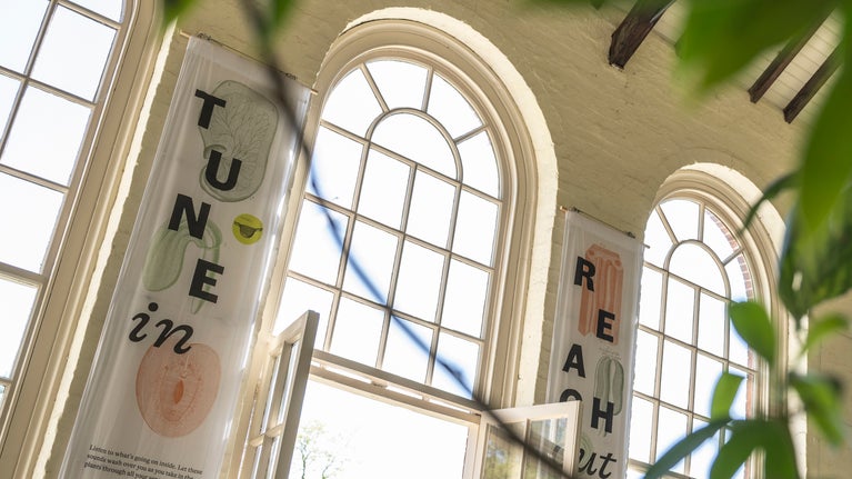 Two large cloth banners hang from the ceiling of The Orangery which read "Tune in